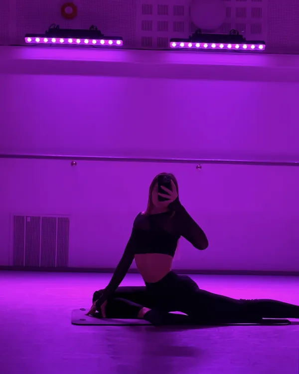 me stretching in a dance studio lit in violet